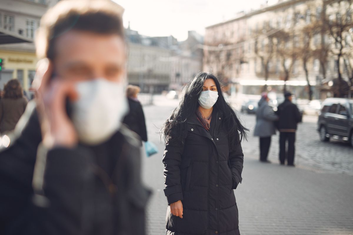 Woman in black coat and face standing on street