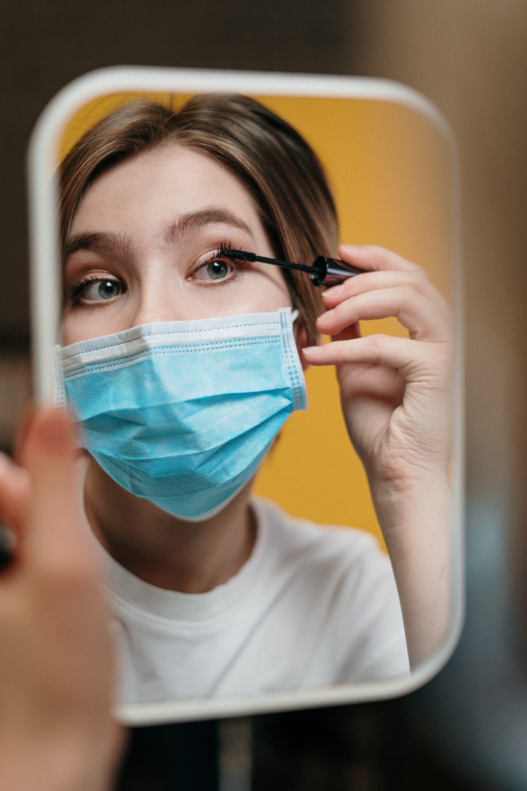 Woman putting on mascara despite the outbreak