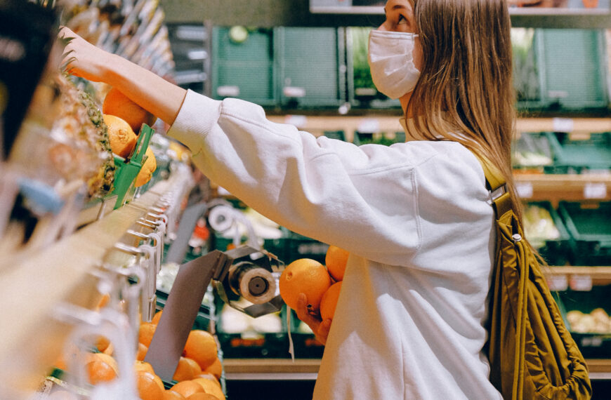 Woman in white long sleeve jacket shopping for fruits