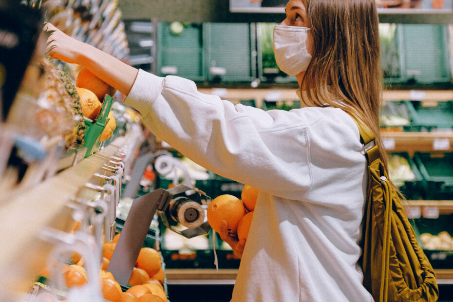 Woman in white long sleeve jacket shopping for fruits
