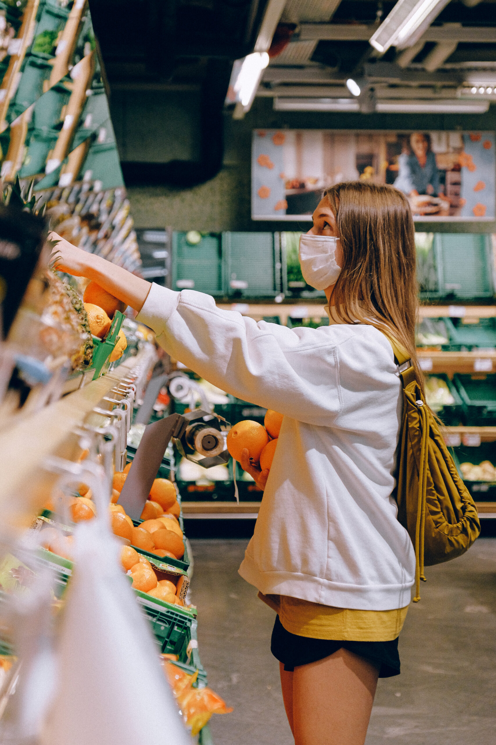 Woman in white long sleeve jacket shopping for fruits