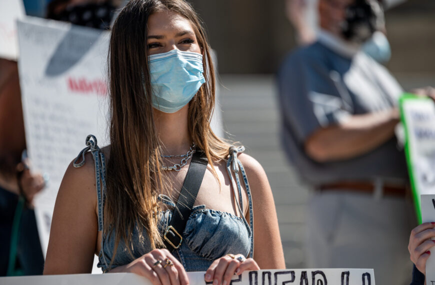 Young woman in mask protesting on street